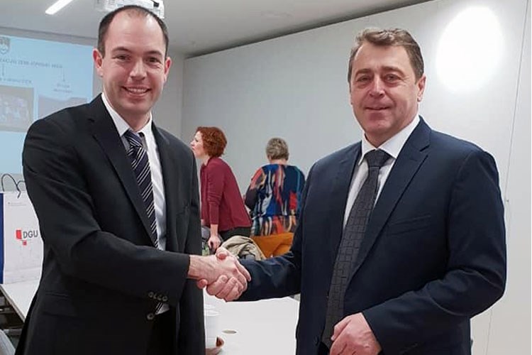 Slika prikazuje fotografiju glavnog ravnatelja Državne geodetske uprave i predsjednika komisije za standardizaciju zemljopisnih imena Republike Slovenije.
