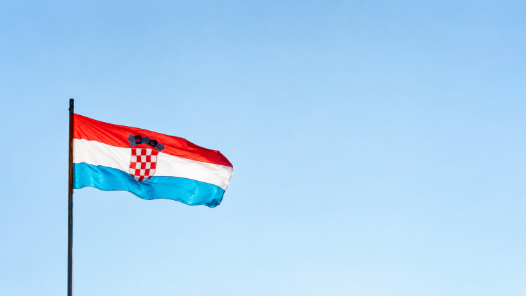 Hrvatska zastava na jarbolu ispred vedrog neba.